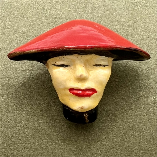 Plaster button of a woman in flat red hat.