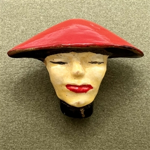 Plaster button of a woman in flat red hat.