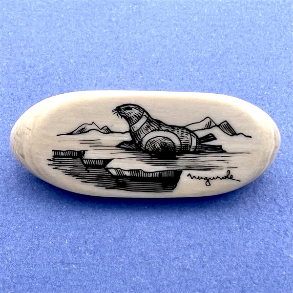 Scrimshaw button of a seal on natural material.