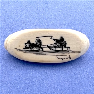 Scrimshaw button of an Eskimo riding in a dogsled on natural material.