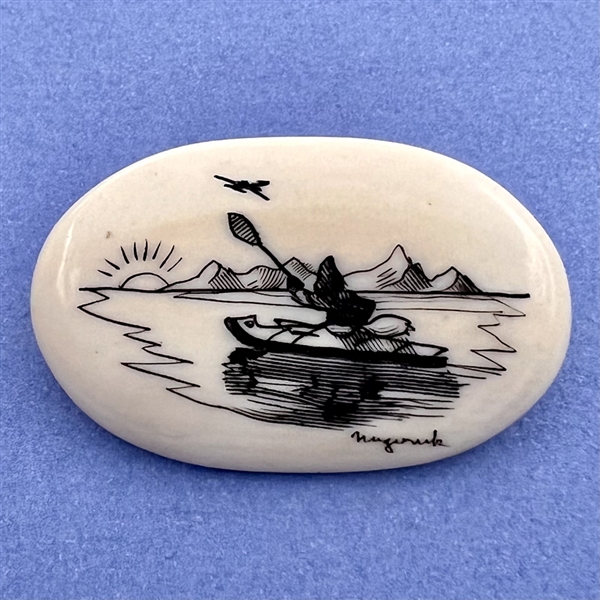 Scrimshaw button of an Eskimo paddling a kayak on natural material.