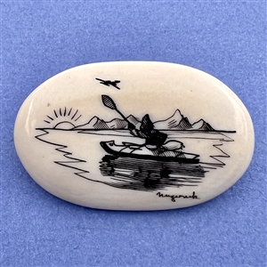 Scrimshaw button of an Eskimo paddling a kayak on natural material.