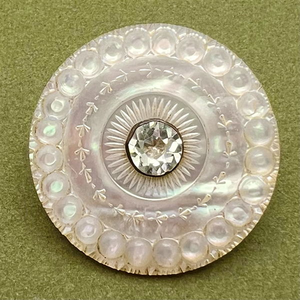 An 18th c. carved mother of pearl button with faceted paste center.