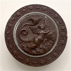 Gutta Percha button of cherub riding a dragon.