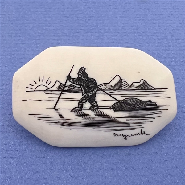 Scrimshaw button of an Eskimo hunting on natural material.