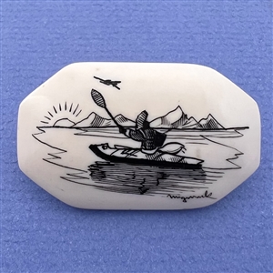 Scrimshaw button of an Eskimo kayaking at sunrise on natural material.