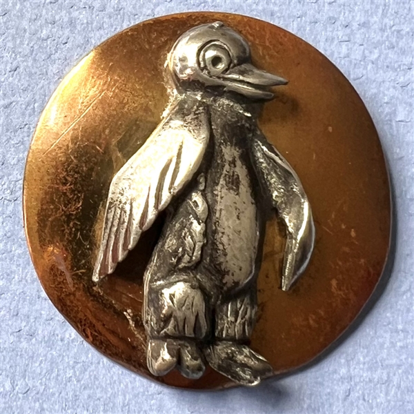 Brass and white metal penguin button.