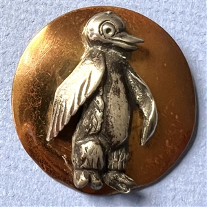 Brass and white metal penguin button.