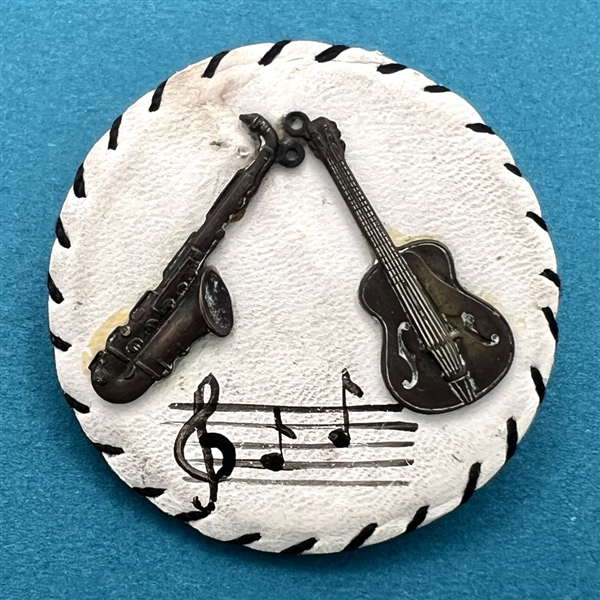 Vintage white leather button with musical instruments.