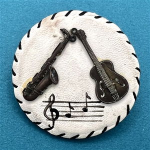 Vintage white leather button with musical instruments.