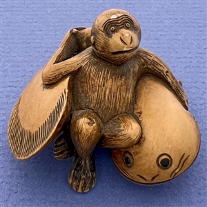 Monkey holding a fish netsuke.