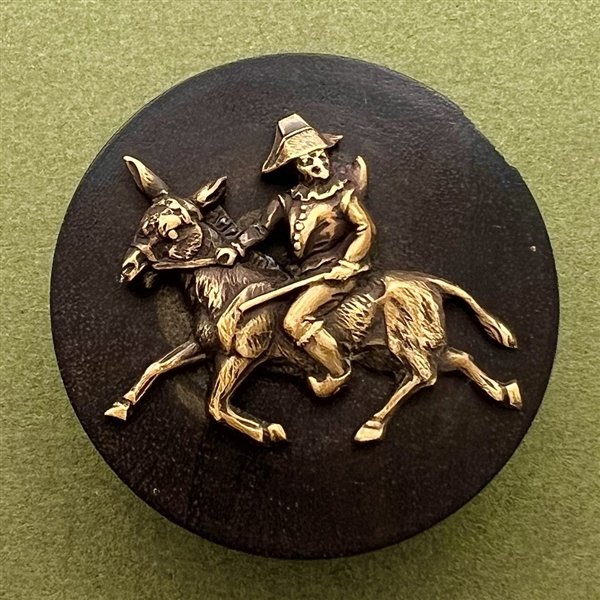 Wood button of Punchinello riding a donkey.