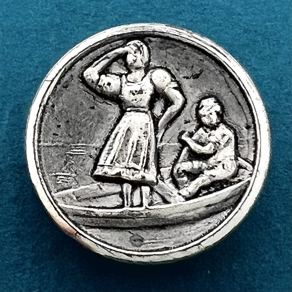 Stamped white metal button of a woman standing in a boat with a man.