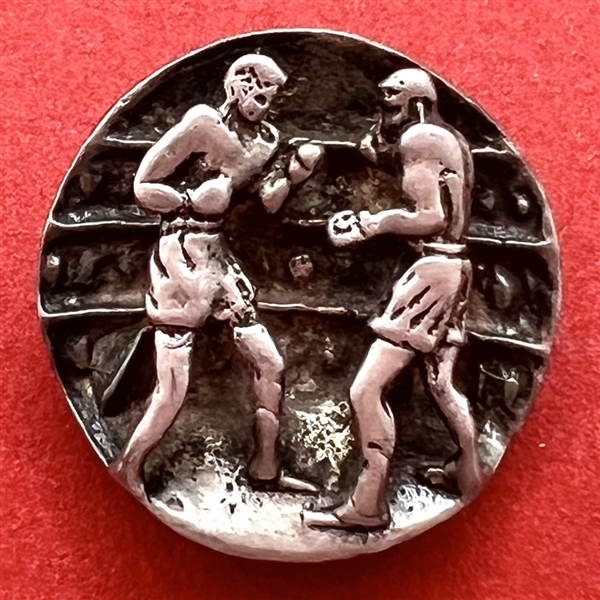 Sculptural button of boxers in a boxing ring.