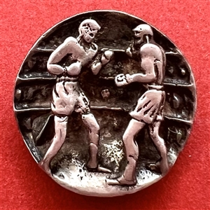 Sculptural button of boxers in a boxing ring.