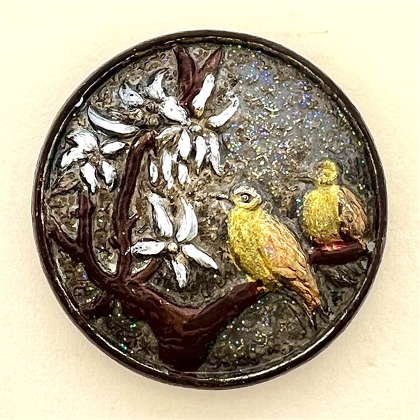 Copper button of two birds on a branch.