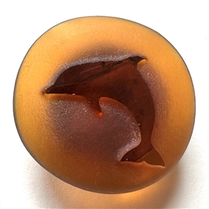 Amber glass button of a dolphin.
