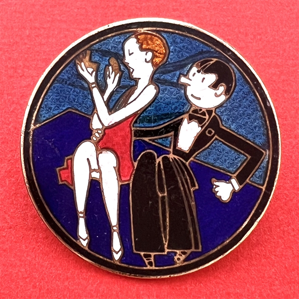 A champlevé enamel button of a man and woman out on the town.