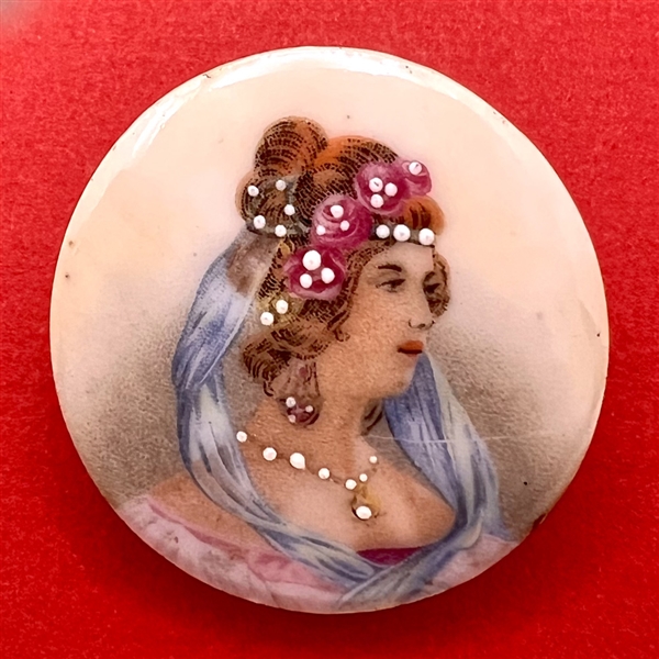 Ceramic button of a woman in veils and pearls.