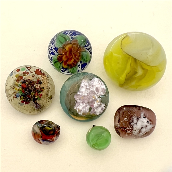 Seven assorted glass studio paperweight buttons.