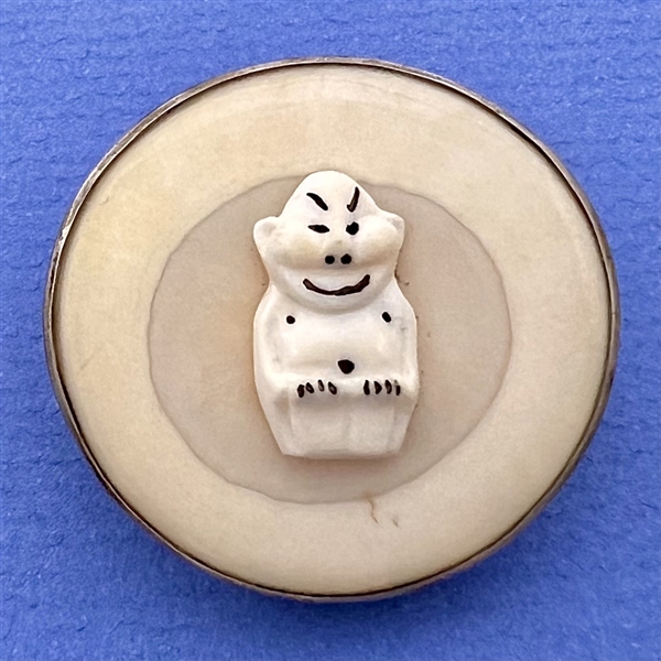 Natural material button of a Billiken.