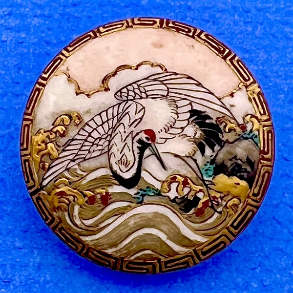 Satsuma button of a crane over waves with Greek key border.