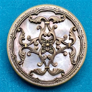 A 19th c. pearl button mounted in metal with a silvered metal Rococo design.