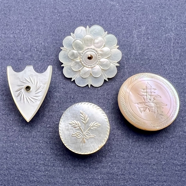 Four assorted incised pearl and shell buttons.