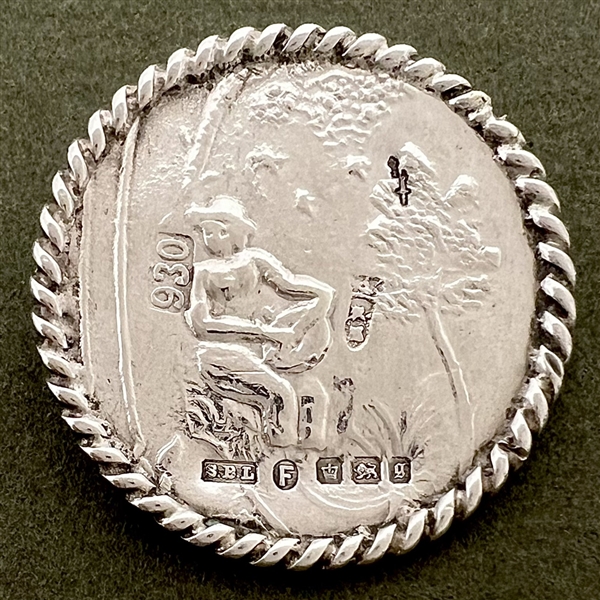 Hallmarked silver button of man playing an instrument in a garden.