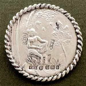 Hallmarked silver button of man playing an instrument in a garden.