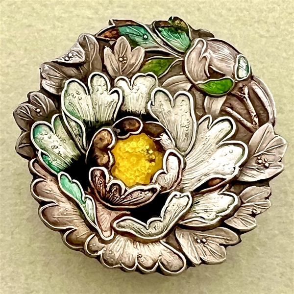 Japanese enamel button of flowers in a garden.