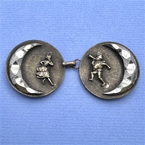 A button closure of brass with a woman and a jester and steel moons.