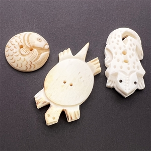 Three carved natural material buttons of animals.