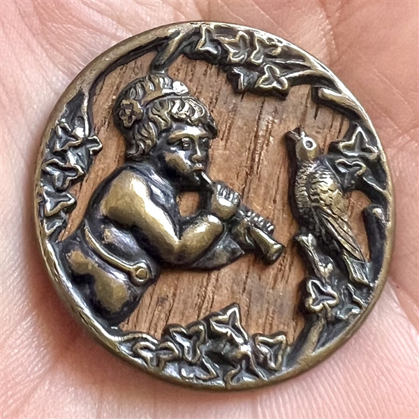 “Putto piping to a bird” brass button.