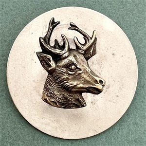 Head of a stag on white metal button.