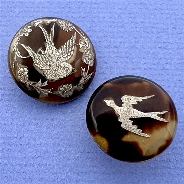 Two tortoise shell with inlay of birds, a stud and a button.