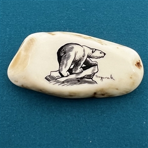 Scrimshaw on natural material button of a polar bear on an ice berg.