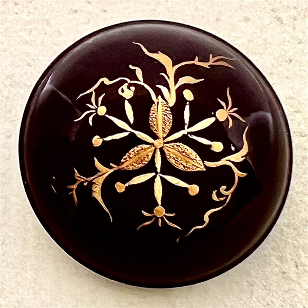 Painted gold plant life on lacquered domed button. 