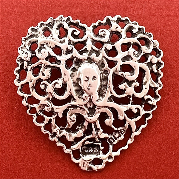 Hallmarked silver button of woman’s face in a heart.