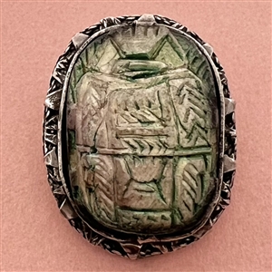 Ceramic button of an Egyptian scarab design set in metal.