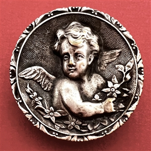 Silvered brass button of a cherub with flowers.