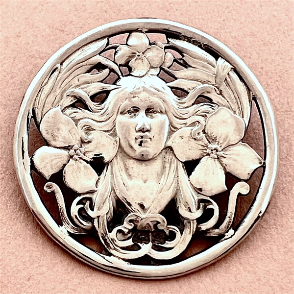 Hallmarked silver button of a woman with plant life.