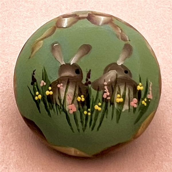 Painted wood studio button of rabbits by Mary Whitaker.