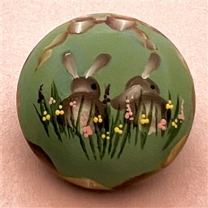 Painted wood studio button of rabbits by Mary Whitaker.