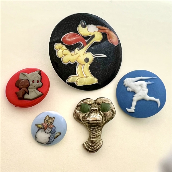 Five assorted buttons of cartoon characters etc.