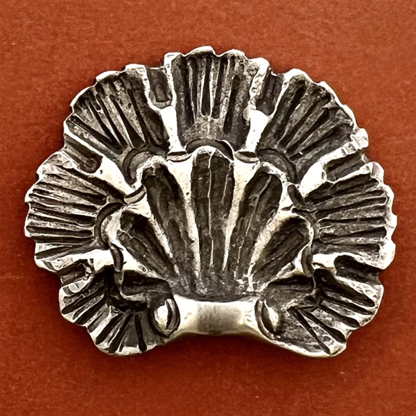 White metal button of a realistic scallop shell.