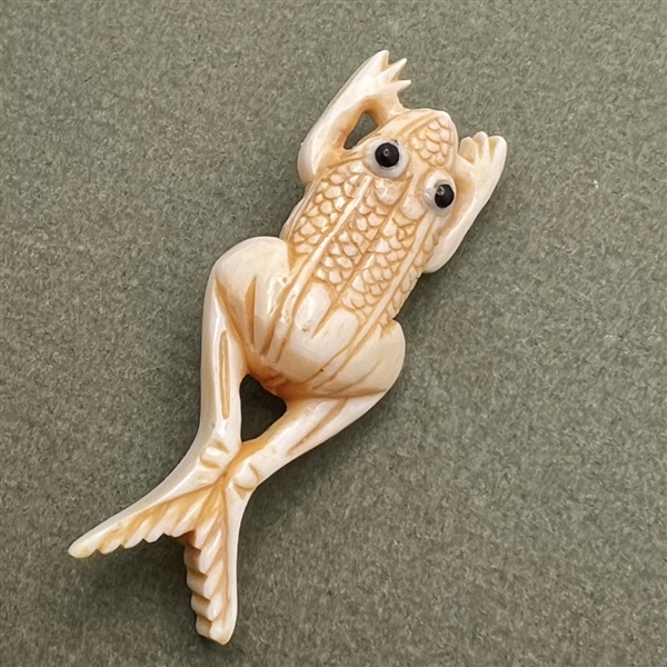 Carved natural material button of a frog.