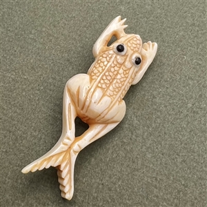 Carved natural material button of a frog.