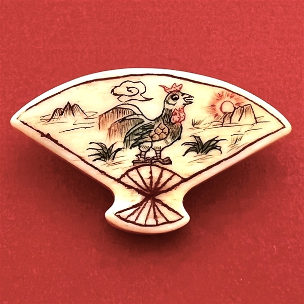 Carved natural material button of a fan decorated with a rooster.