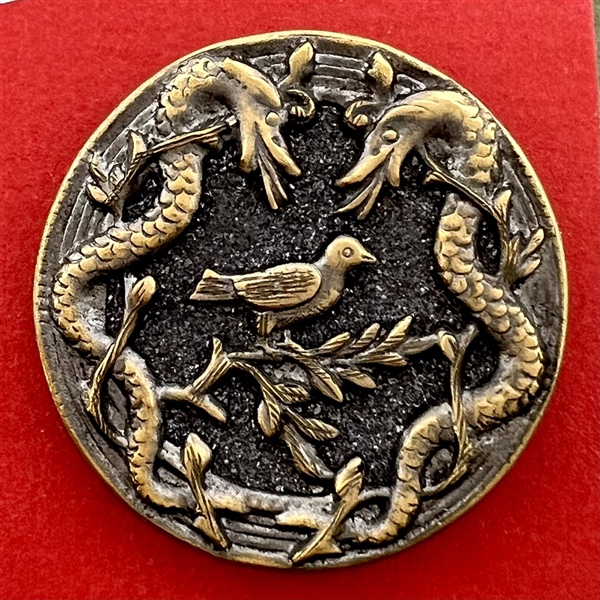 Brass button with galena of a bird surrounded by two snakes.